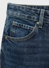 Pantalón de jean azul oscuro con tiro medio, diseño de corte recto, cinco bolsillos, presillas para cinturón y cierre frontal con botón y cremallera.