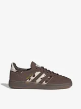Championes Adidas Handball Spezial, color marrón con detalles de textura animal print en las icónicas tres tiras y en el talón. Presenta el nombre del modelo estampado en dorado en el lateral y suela de goma semitransparente.