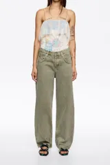 Pantalón de denim color verde oliva, tiro bajo, corte barrel (tobillero y ancho), con cierre de botones frontales y diseño de cinco bolsillos.