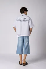 Camisa de manga corta de popelina rayada, con calce boxy y bordado sutil en el pecho. Presenta cierre frontal con botones y diseño abierto.