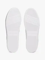 Zapatillas de tenis Tommy Hilfiger de corte bajo, confeccionadas en piel napa blanca con paneles de textura en color verde claro en el talón. Presentan suela gruesa de goma, cierre con cordones y logo metálico en bajo relieve en el lateral.