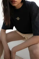 Remera oversize de algodón con efecto gastado, color marrón, con estampado gráfico en la espalda que incluye un sol sonriente, laureles y texto temático de viaje.