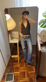 Top negro de estilo halter con espalda descubierta y tiras ajustables para atar. Confeccionado en tejido elástico, presenta un diseño versátil y moderno.