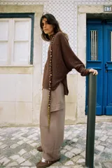 Jersey de punto color marrón con cuello subido y manga larga. Presenta un diseño de cuerpo amplio estilo capa con sisa ancha y bajo asimétrico con aberturas laterales.