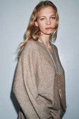 Jersey oversize color beige melange, confeccionado con lana, con cuello en V y manga larga.