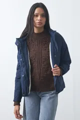 Campera acolchada de nylon color negro, con cuello alto, cierre frontal y botones a presión. Presenta un diseño de rombos y forro interior suave.