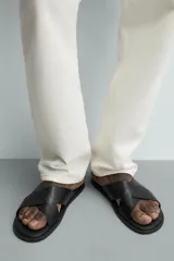 Sandalia plana de cuero negro con dos tiras anchas cruzadas en el empeine y plantilla anatómica.