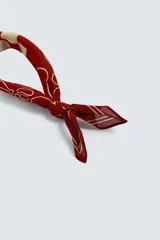 Bandana cuadrada confeccionada en tejido fluido de lyocell, color bordó con estampado en contraste beige. Presenta un diseño central de cuadros rodeado de motivos abstractos y caligrafía.