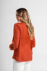 Camisa verde con cuello mao, de manga larga con puños abotonados y cierre frontal con botones.