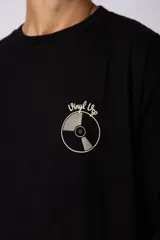 Remera negra de corte oversize con estampa pequeña en el pecho que representa un disco de vinilo con la inscripción Vinyl Up.