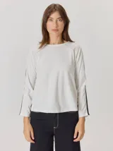 Remera de manga larga color blanco, con cuello redondo y detalle de costuras en contraste en la parte superior de los hombros.