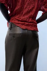 Pantalón de tiro medio confeccionado en 100% piel de color marrón, con diseño flare y costuras decorativas.