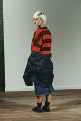 Jersey de punto a rayas horizontales en color marrón y rojo, con cuello polo y cierre frontal parcial, de manga larga y diseño holgado.