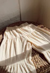 Pantalón beige de corte palazzo, con cintura elástica y diseño escalonado.