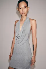 Vestido corto de punto con hilo metalizado color plateado, cuello halter con escote fluido y espalda descubierta.