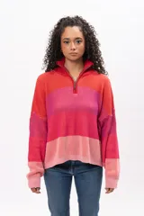 Buzo de tejido de punto con diseño a rayas horizontales en tonos degradados de rojo y rosa. Presenta cuello alto con cierre frontal parcial, mangas largas y corte holgado.