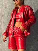 Bermuda de tiro alto en color rojo, confeccionada en cuero sintético, con costuras a la vista en contraste, cierre frontal y bolsillos laterales.