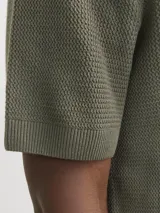 Polo de manga corta confeccionado en tejido de punto estructurado con textura sutil. Presenta cuello clásico, cierre frontal con botones y terminaciones acanaladas en mangas y ruedo.