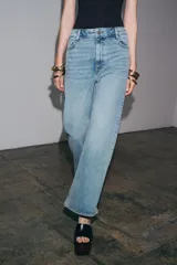 Jeans de tiro alto y corte ancho (wide leg) hasta el tobillo, confeccionados en denim azul de efecto lavado. Presenta cinco bolsillos y cierre frontal con cremallera y botón.