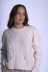 Sweater color crema de punto con diseño de ochos y flores bordadas. De corte holgado y mangas largas.