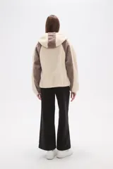 Campera de abrigo de tejido polar (tipo sherpa) color gris oscuro, con capucha y cierre frontal. Presenta paneles de color negro en los hombros y mangas, ribeteados con un vivo de color claro.