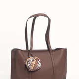 Cartera tipo tote de cuero sintético en color marrón, con textura granulada, doble asa de hombro y un pequeño monedero circular colgante con estampado animal print.