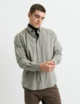 Camisa de franela lisa con cuello button-down, manga larga, botones al tono y bolsillo frontal en el pecho.