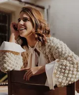 Cardigan de lana merino color beige, tejido a mano en punto garbanzo, con semi cuello alto y diseño abierto en la parte delantera.