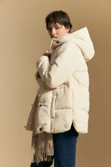 Campera acolchada de nylon en color crema, con capucha ajustable, cierre frontal con botones y cordón de ajuste en la cintura.