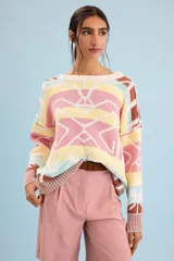 Buzo oversize de punto color marfil con diseño geométrico jacquard en tonos rosado, amarillo, celeste y marrón. Cuenta con cuello redondo y mangas largas.