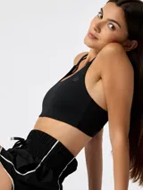 Top deportivo negro con escote redondo, doble tirante fino y sutil logo estampado en el pecho.