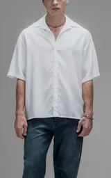 Camisa de manga corta con cuello cubano, corte oversize y cierre frontal de botones. Confeccionada en tejido de lyocell, presenta un diseño minimalista y liso.