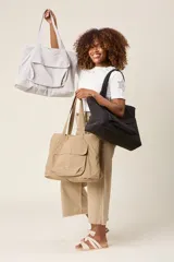 Bolso tote color beige, de tela tipo paracaídas, con doble asa de mano y bolsillo frontal con solapa.