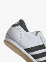 Zapatillas Adidas de cuero blanco con las tres tiras laterales en negro y suela de goma color caramelo.