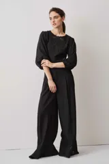 Blusa negra con detalles de apliques bordados en el pecho y las mangas, cuello redondo y mangas largas abullonadas.
