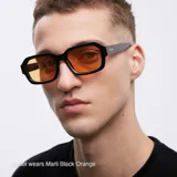 Lentes de sol rectangulares unisex, con montura fina negra y lentes color naranja.