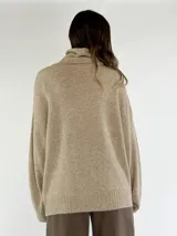 Sweater de punto color beige con cuello alto, diseño de rombos en relieve y detalle de lentejuelas aplicadas en el frente.