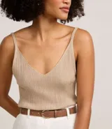 Blusa musculosa de punto canelado con hilo metalizado, escote en V y tirantes finos. Presenta un acabado brillante y un ajuste al cuerpo.