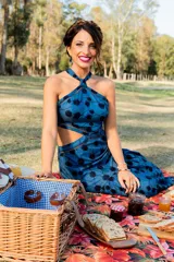 Vestido largo azul con estampado de flores negras, escote halter con detalle cruzado y aberturas laterales en la cintura.