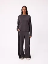 Sweater de corte oversize y estilo cropped, color gris oscuro, con cuello redondo y detalle de costura en forma de X en el pecho. Presenta un pequeño logo bordado en el ruedo inferior.