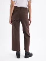 Pantalon de corte recto y ancho, color marrón, con costuras verticales decorativas en el frente y cierre de botón y cremallera.