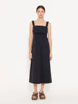 Vestido midi negro de poplin con lycra, silueta línea A, bolsillos plaqué en los laterales y tajo en el centro delantero. Se ajusta en la espalda mediante un lazo.