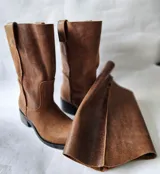 Bota de cuero marrón con diseño 2 en 1, que incluye una polaina desmontable. Presenta una caña alta estructurada y una base de bota tipo botineta con suela plana de goma negra.