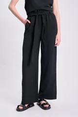 Pantalón negro de corte palazzo con lazo en la cintura y textura arrugada.
