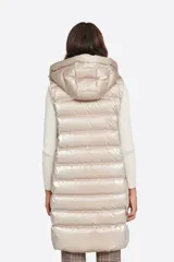 Chaleco largo azul con capucha desmontable, cierre central con cremallera de doble carro y bolsillos con tapa. Diseño acolchado a rayas horizontales. Largo 86cm.