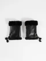 Mitones de cuero sintético negro con interior de piel sintética y bordes de pelo. Presentan un detalle de acordonado lateral ajustable con pompones en los extremos.