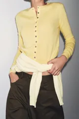 Cardigan de punto en tejido 100% cashmere, color verde oliva, con cuello redondo, manga larga y cierre frontal con botones. Presenta terminaciones en rib en puños y ruedo.