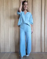 Pantalón de denim estilo palazzo, color azul claro, con cintura elástica en la parte posterior, bolsillos frontales y costuras verticales decorativas a lo largo de las piernas.