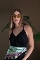 Lentes de sol con marco verde y cristales naranjas, de forma ojo de gato angular.