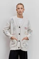 Cardigan de punto azul con cuello en V, cierre frontal de botones y bolsillos delanteros. Presenta bordados decorativos con motivos variados y frases en colores contrastantes.